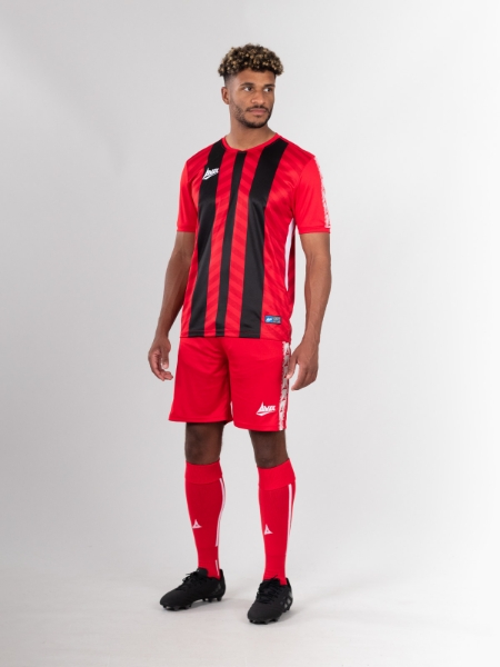 A red and black stripe football shirt is worn as a full kit with red shorts and red socks