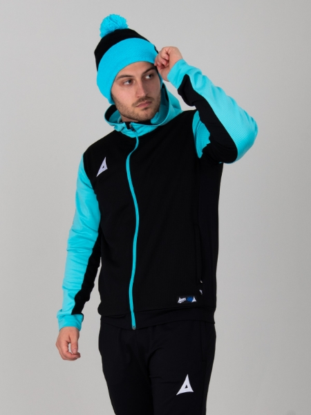 A male is standing up wearing a black and light blue bobble hat