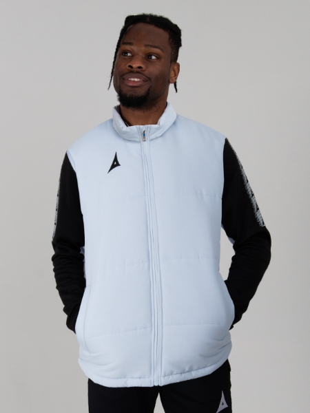 A man wearing a light grey Gilet over the top of a black jacket.