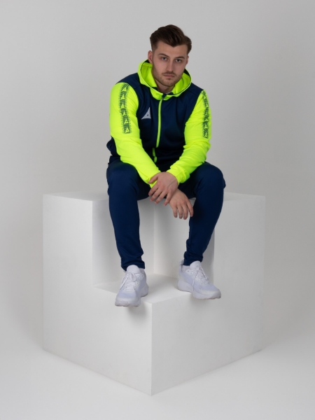 A man sitting on a cube wearing a bright navy and yellow full zip hoody