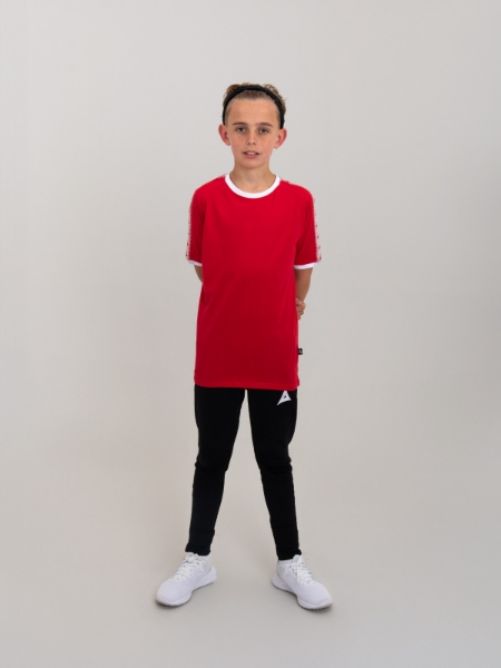 A child is standing up, wearing a red cotton t-shirt with white details. 