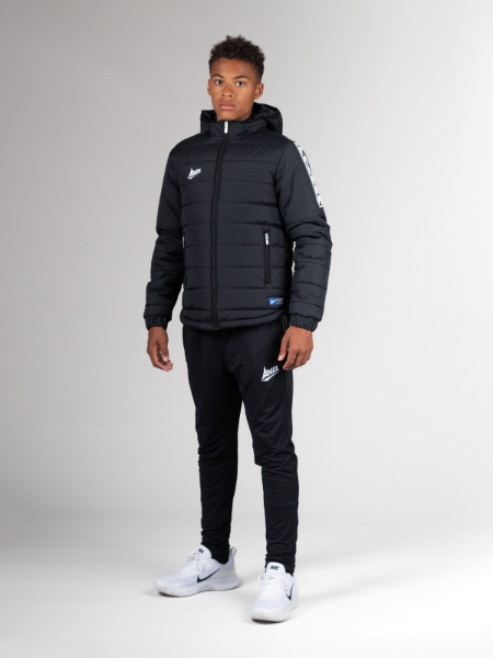 An teenager is wearing black joggers which are slim fitting, while wearing a coat.