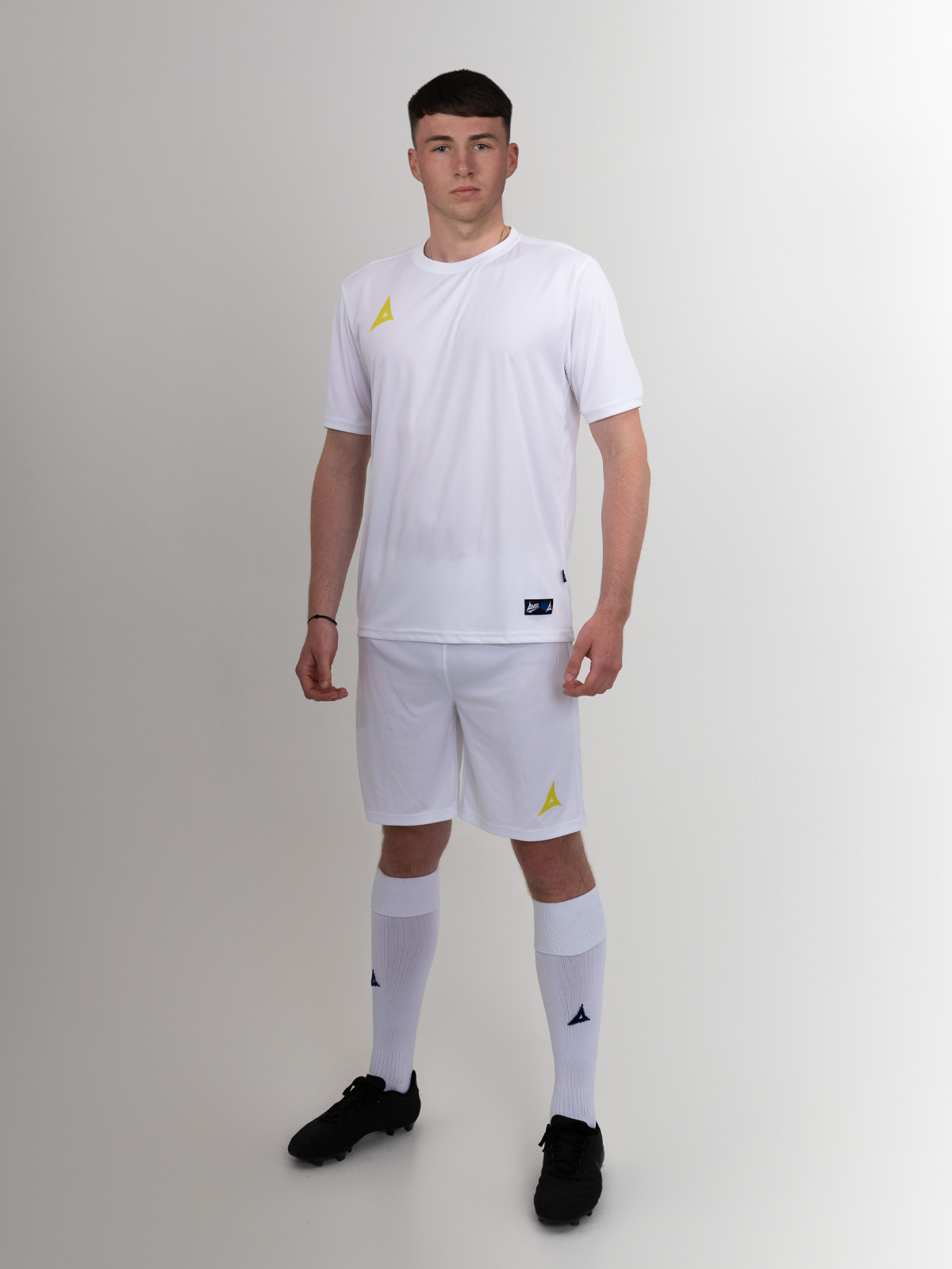 a complete white football kit with yellow logos is being worn by this man.