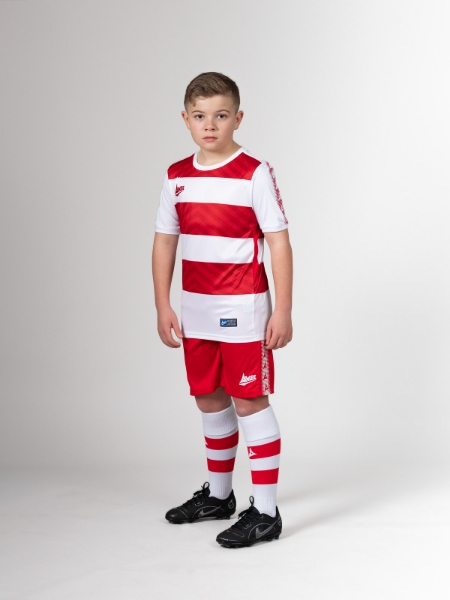 This child is wearing red shorts with his red and white hoop football shirt