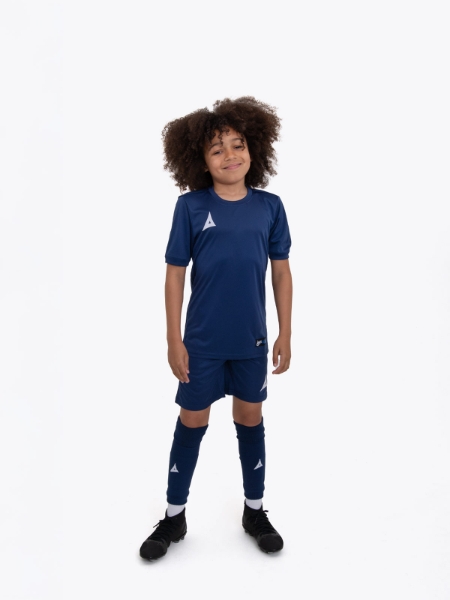 A boy is stood with his hands by his side with navy shorts on matching his t-shirt.