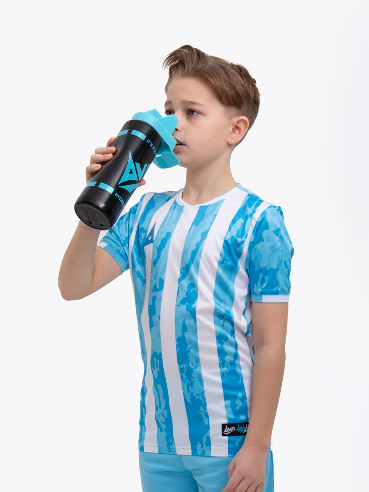 a kid is wearing a sky blue football shirt with white stripes and is drinking from a black hydration hygiene bottle with a no touch spout 