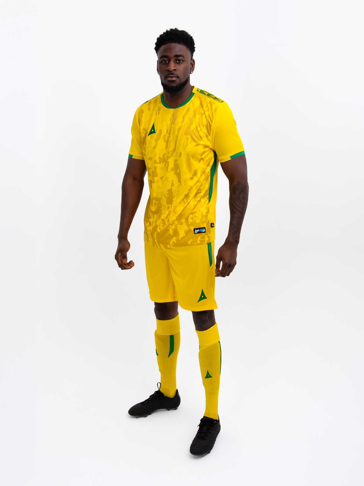 a model standing up wearing a yellow and green football shirt, yellow shorts and yellow football socks.