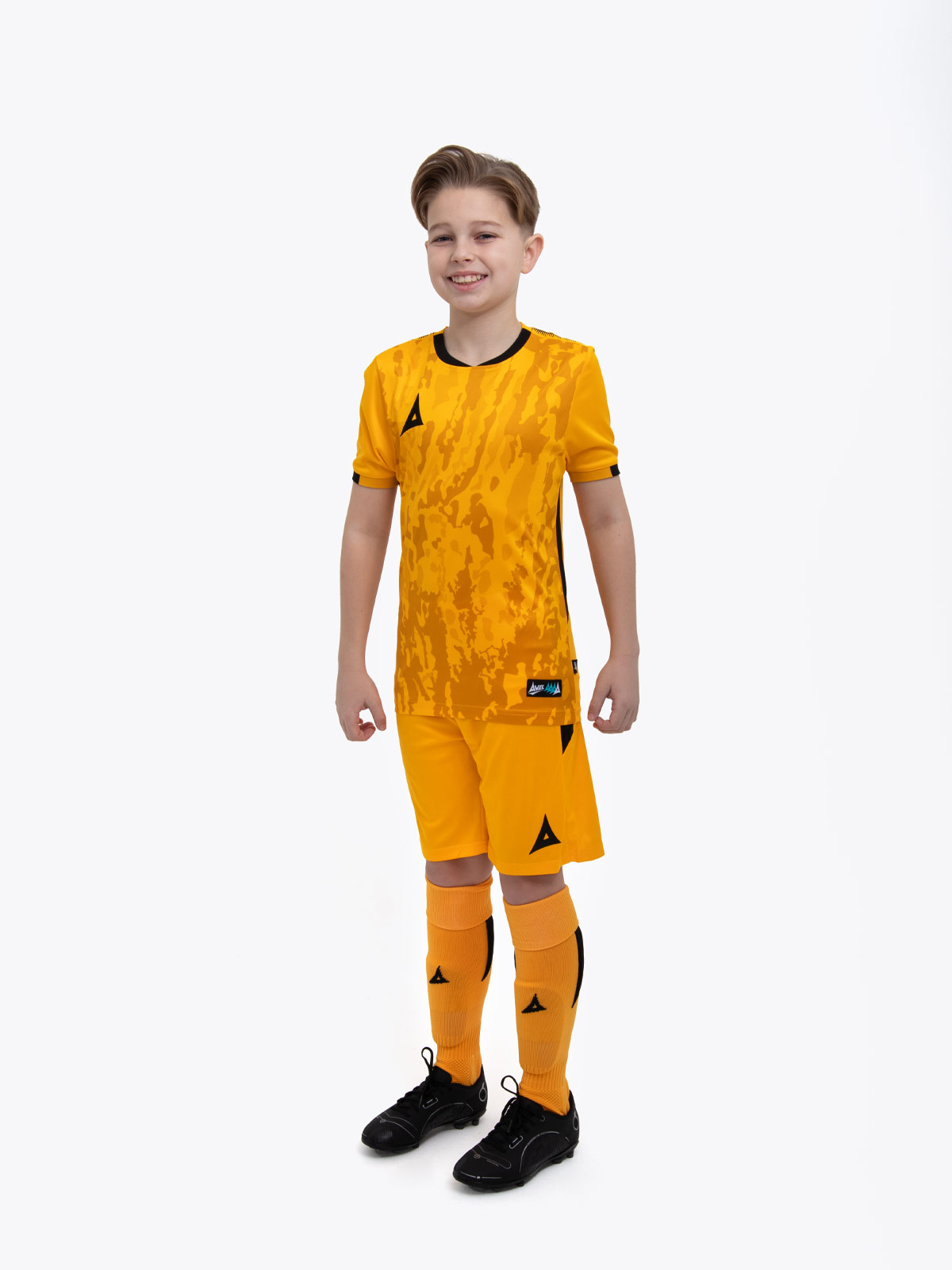 a kids football kit in amber with black details and matching amber shorts and socks
