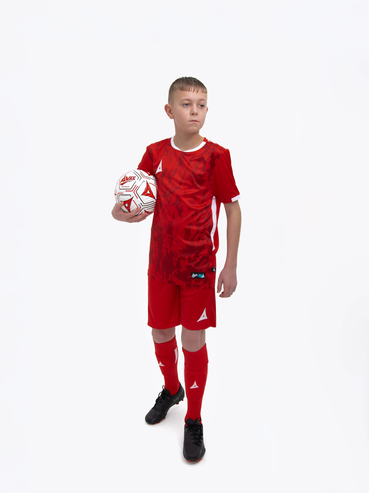 a young child is wearing a red football shirt. the football shirt has a camo pattern and matching red socks and shorts