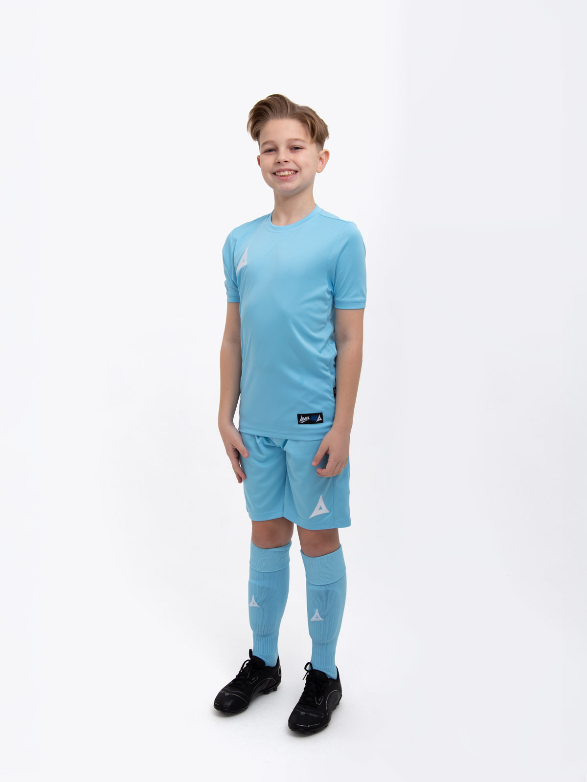 a young child is wearing a sky blue football shirt. he has matching shorts and socks