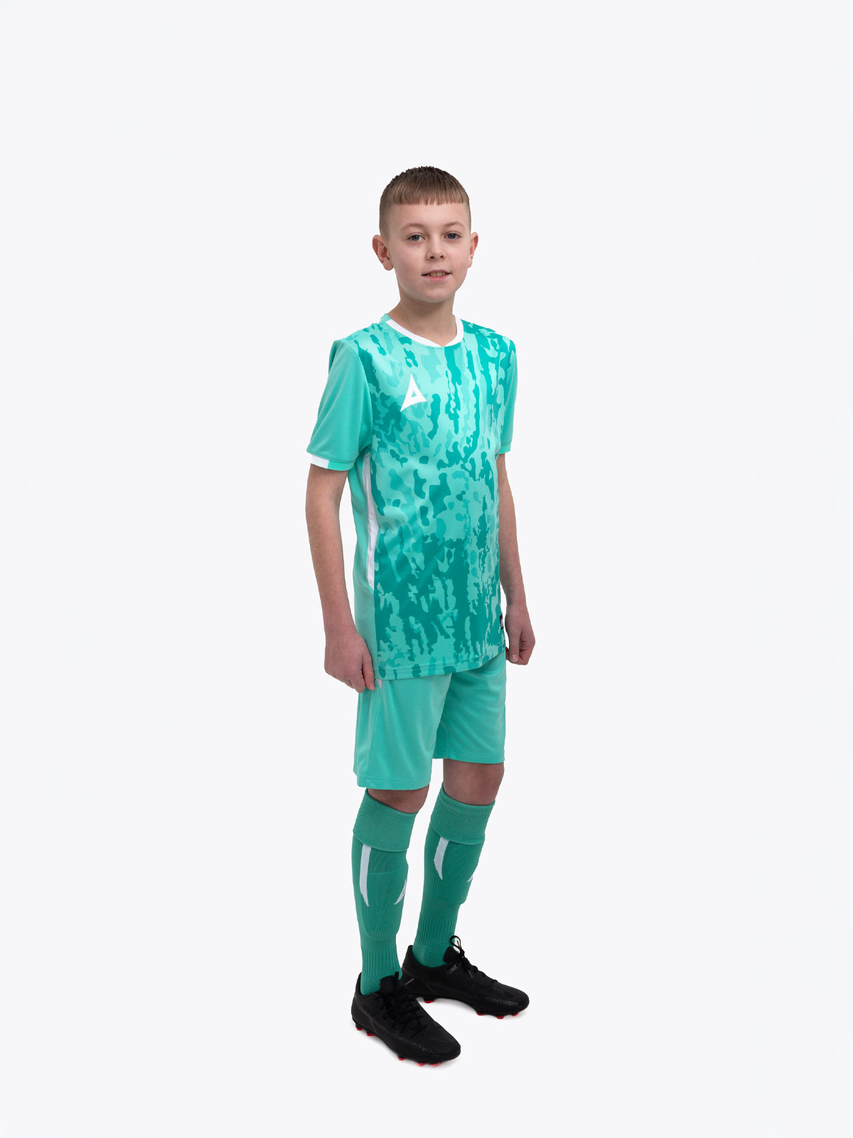 a kid standing up wearing a mint green / hyper green football shirt, matching hyper green shorts and hyper green football socks.