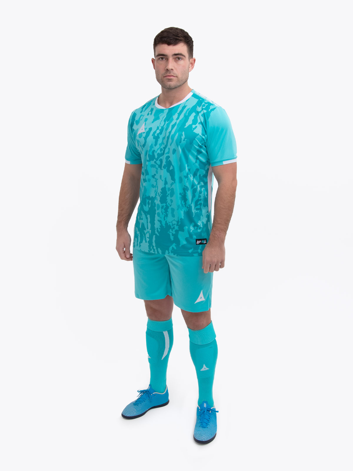 a model standing up wearing a hyper blue football shirt, matching hyper blue shorts and football socks.