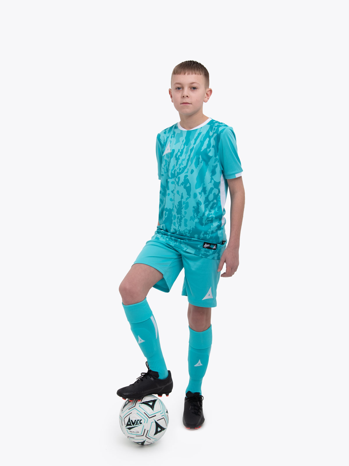 a kid standing up wearing a hyper blue football shirt, matching hyper blue shorts and football socks.
