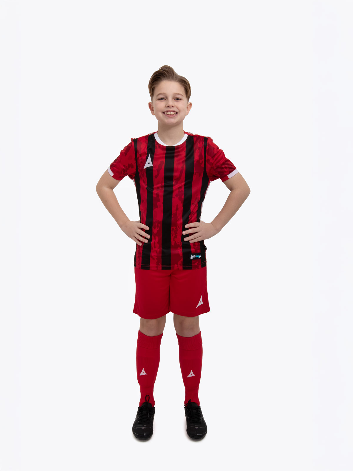 a kids football kit in red and black with stripes and matching red shorts and socks