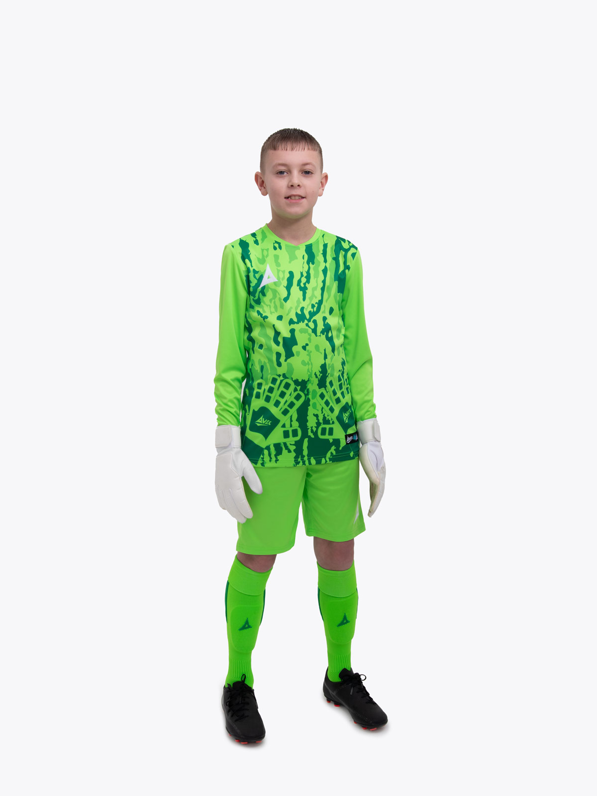 a kid standing up wearing a neon green goalkeeper football shirt, neon green shorts and neon green football socks.