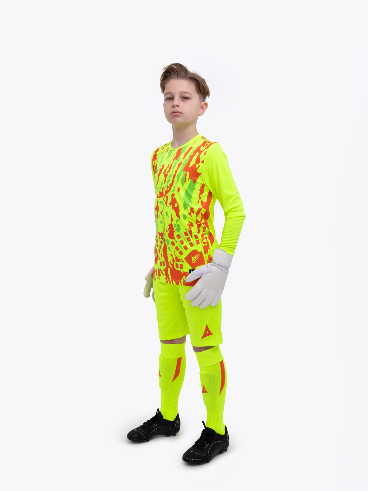 a young boy is wearing a full neon yellow goalkeeper football kit with an orange trim and detailing
