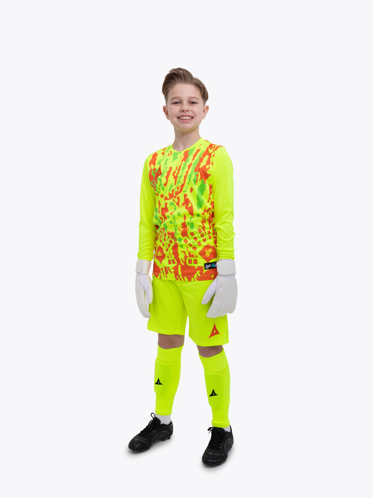 a young boy is wearing a full neon yellow goalkeeper football kit with an orange trim and detailing